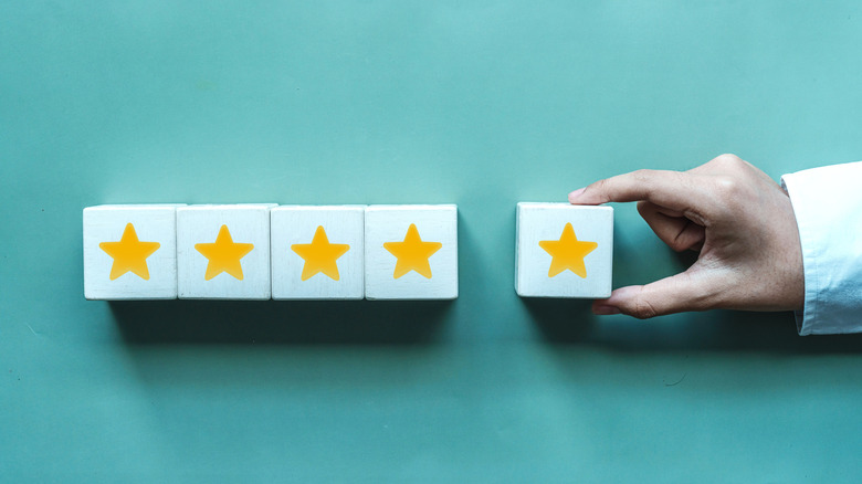 A hand adding fifth star to a four star rating