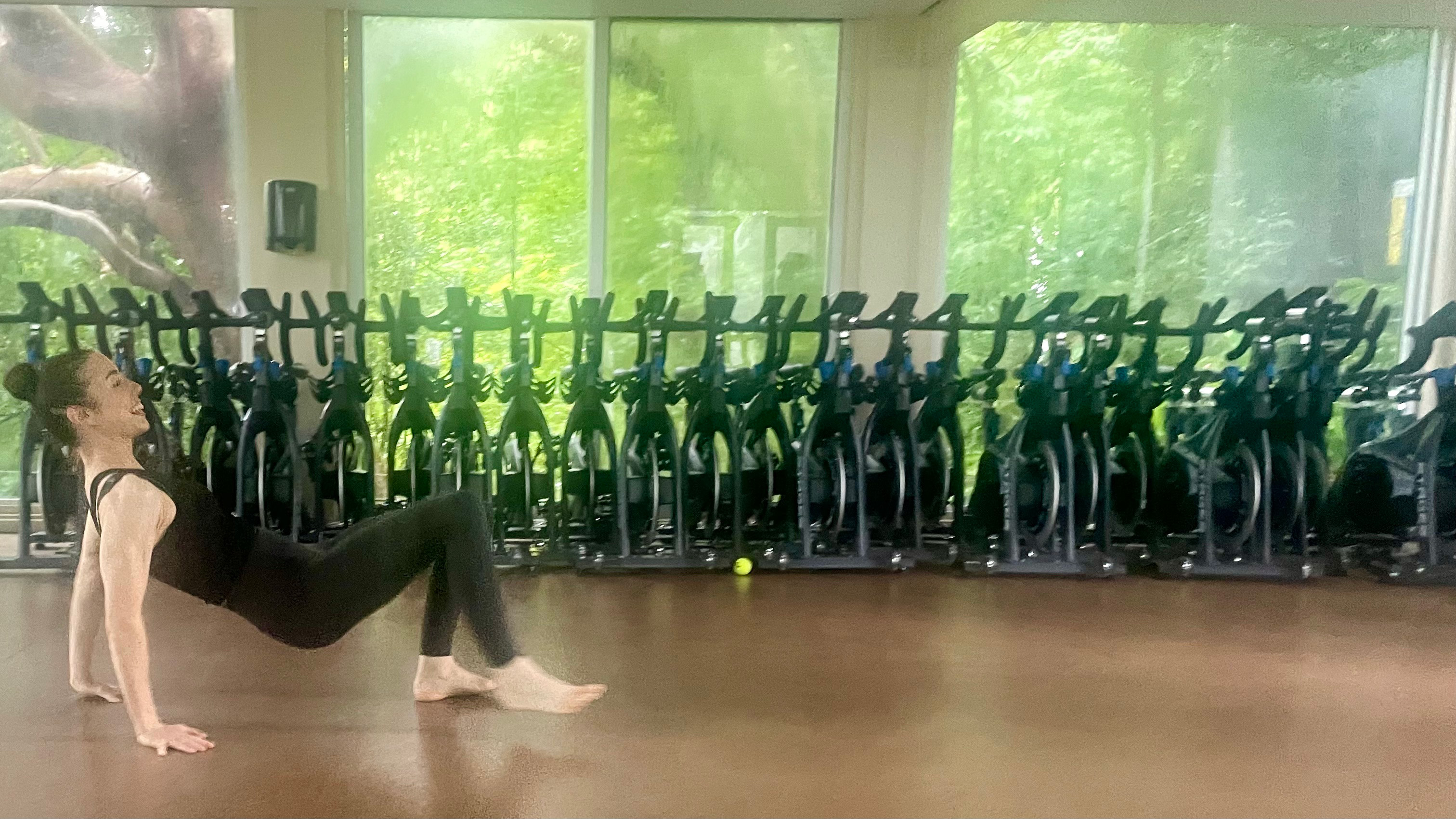 Lucy performing the crab exercise on the ground of a gym studio