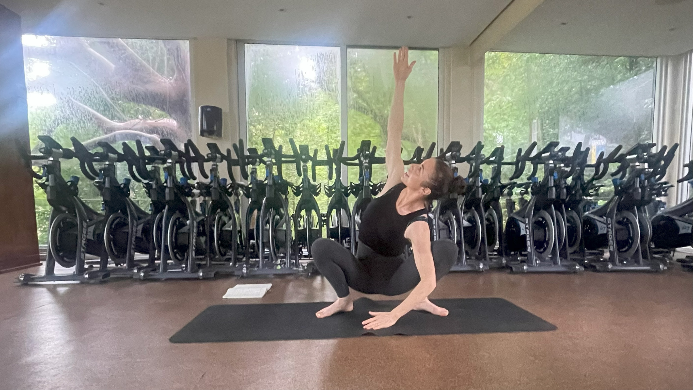 Lucy performing squat rotations in gym studio