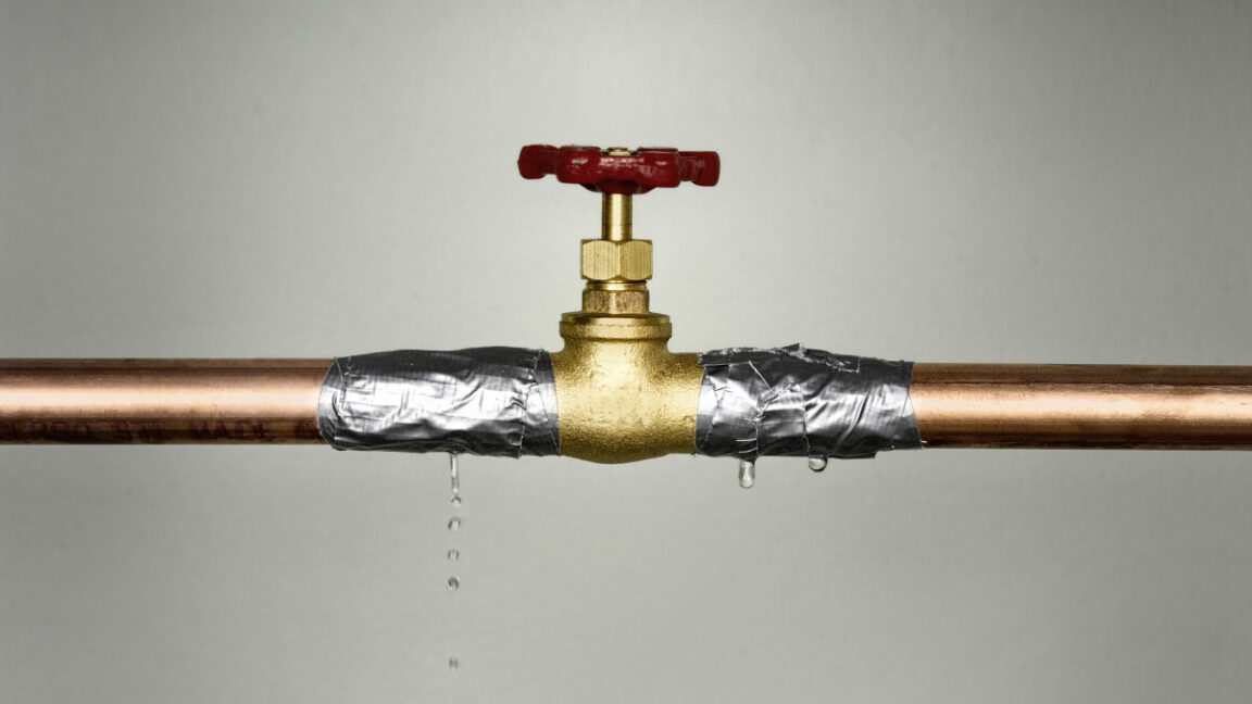 Closeup shot of the leaking water pipe with red valve