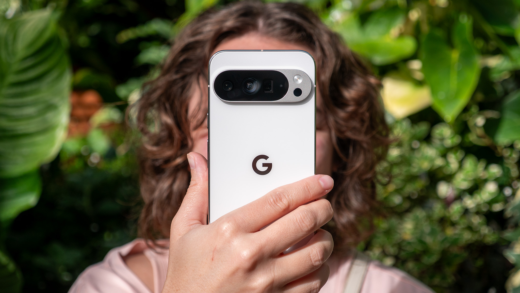 A woman holding up a white Google Pixel 10 Pro XL