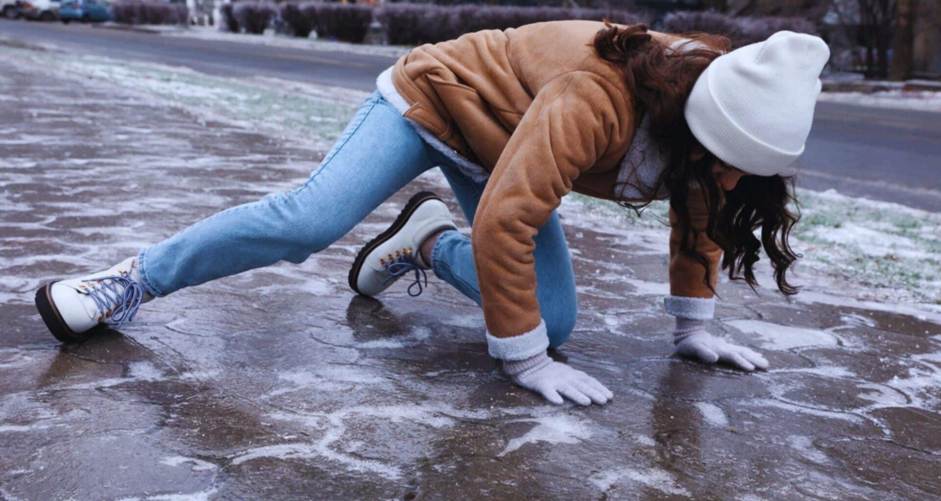 Young Woman Trying To Get Up After Falling On An Icy Sidewalk