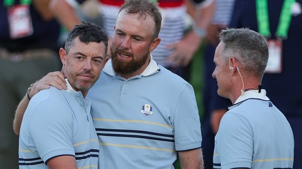 Shane Lowry of Team Europe hugs teammate Rory McIlroy as they talk to Captain Luke Donald of Team Europe after they tied their match with Patrick Cantlay and Sam Burns of Team United States during the Friday afternoon four-ball matches of the 2025 Ryder Cup at Black Course at Bethpage State Park Gol