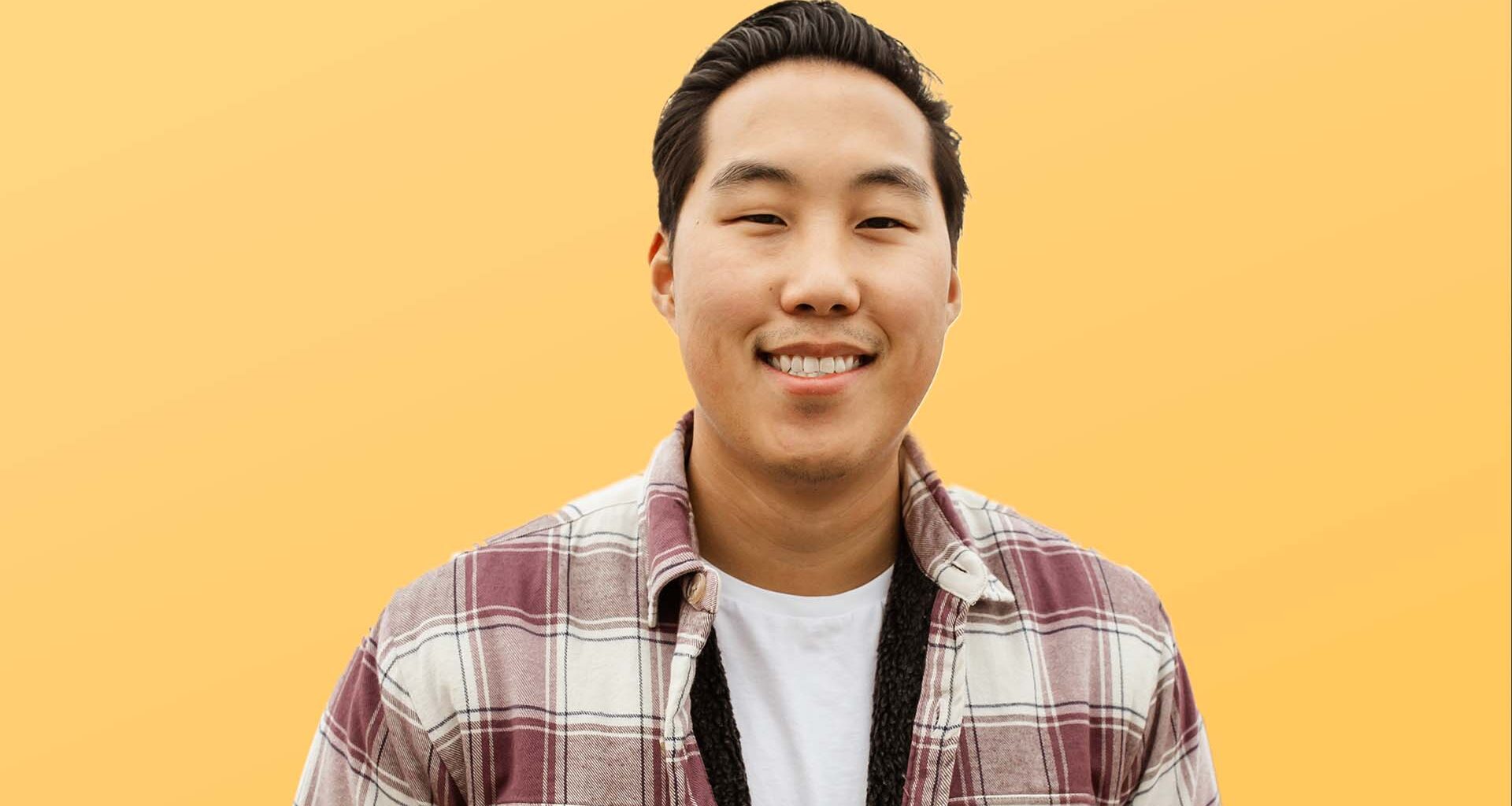 preston seo in a flannel shirt smiling with a yellow background