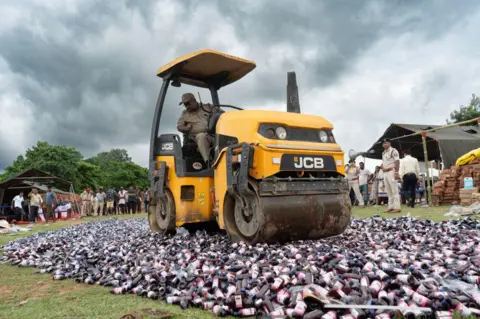 NurPhoto via Getty Images Cough syrups seized from different places being destroyed using road roller by Assam police to mark the Drug Destruction Day, in the outskirt of Guwahati in Assam, India on July 17, 2023. The Central Board of Indirect Taxes and Customs (CBIC) conducts a Drug Destruction Day today. (Photo by David Talukdar/NurPhoto via Getty Images)