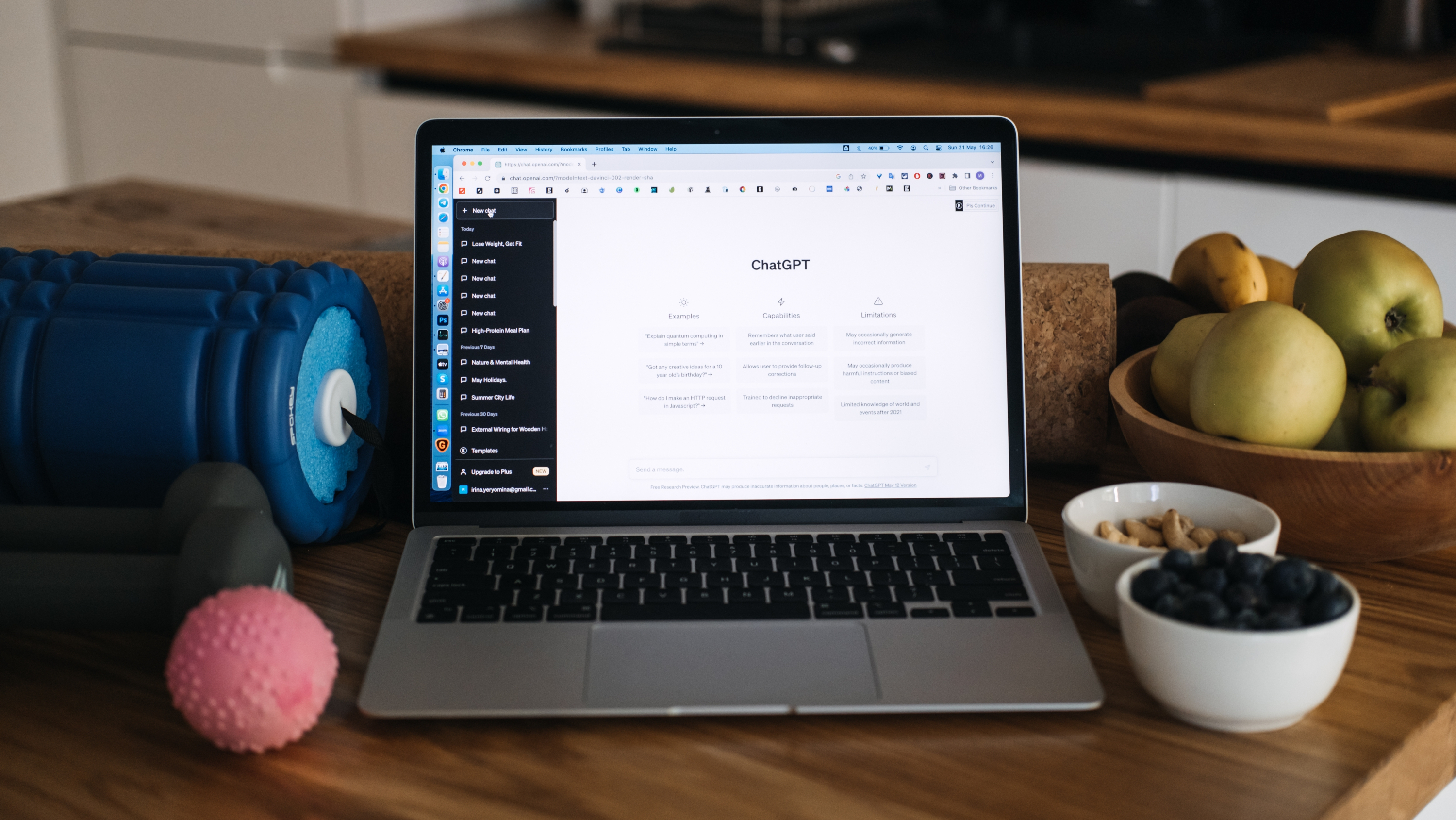 a laptop with ChatGPT on screen and bowls of fruit around and exercise tools around the laptop