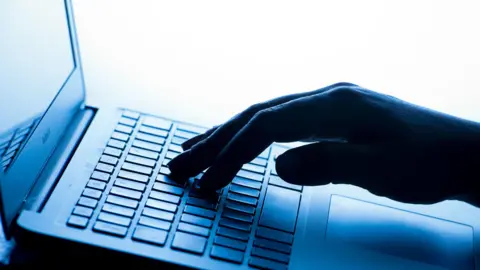 PA News An image of a hand hovering over a laptop key board preparing to type.
