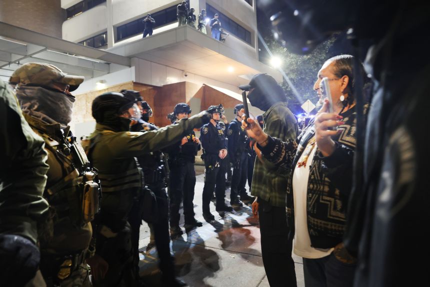 Federal agents, including members of the Department of Homeland Security, and the Border Patrol, hold back protesters outside a downtown U.S. Immigration and Customs Enforcement (ICE) facility yeseterday.