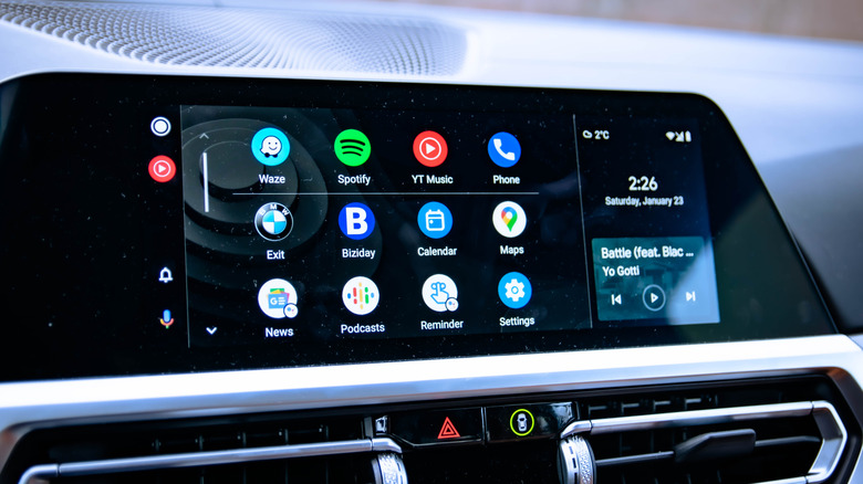 A vehicle's infotainment screen displaying several apps and a music player within Android Auto