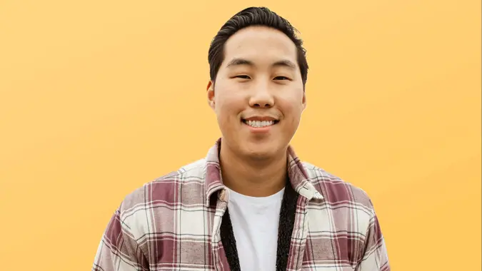 preston seo in a flannel shirt smiling with a yellow background