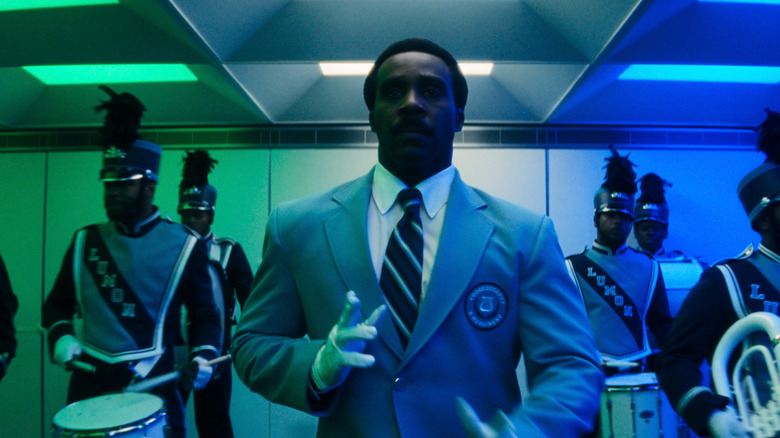 Tramell Tillman as Mr. Milchick leading a choreographed dance with a marching band behind him in Severance