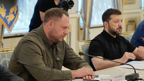 Global Images Ukraine via Getty Images Ukraine's President Volodymyr Zelensky (R) and Head of the Office of the President of Ukraine Andriy Yermak sit at a table