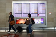 Travelers walk past flight information at Dallas Love Field Airport on Tuesday, Nov. 4,...