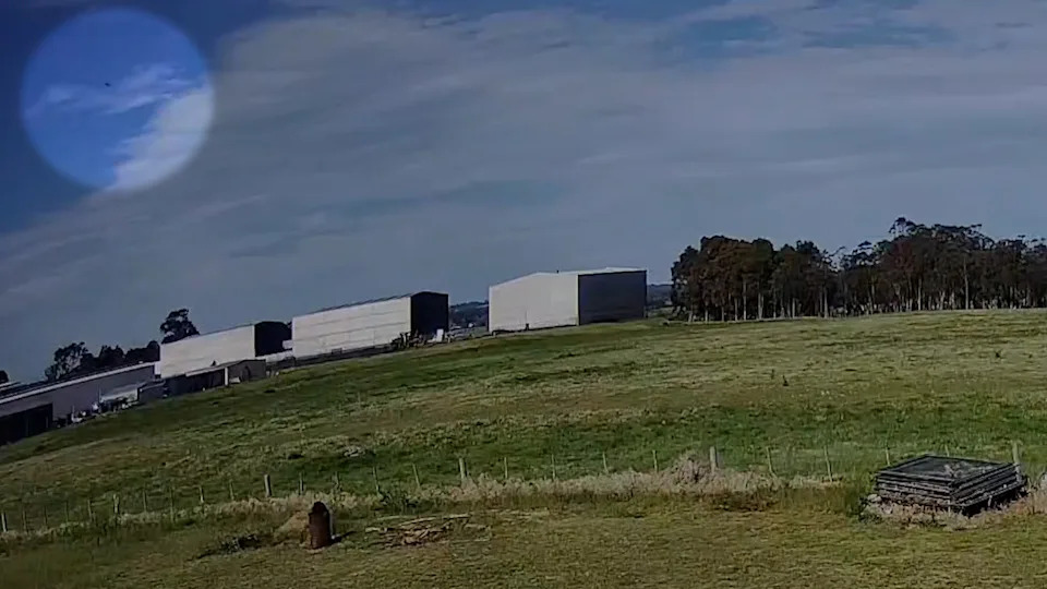 A dark rock in the sky at Bairnsdale. Sheds can be seen below it.