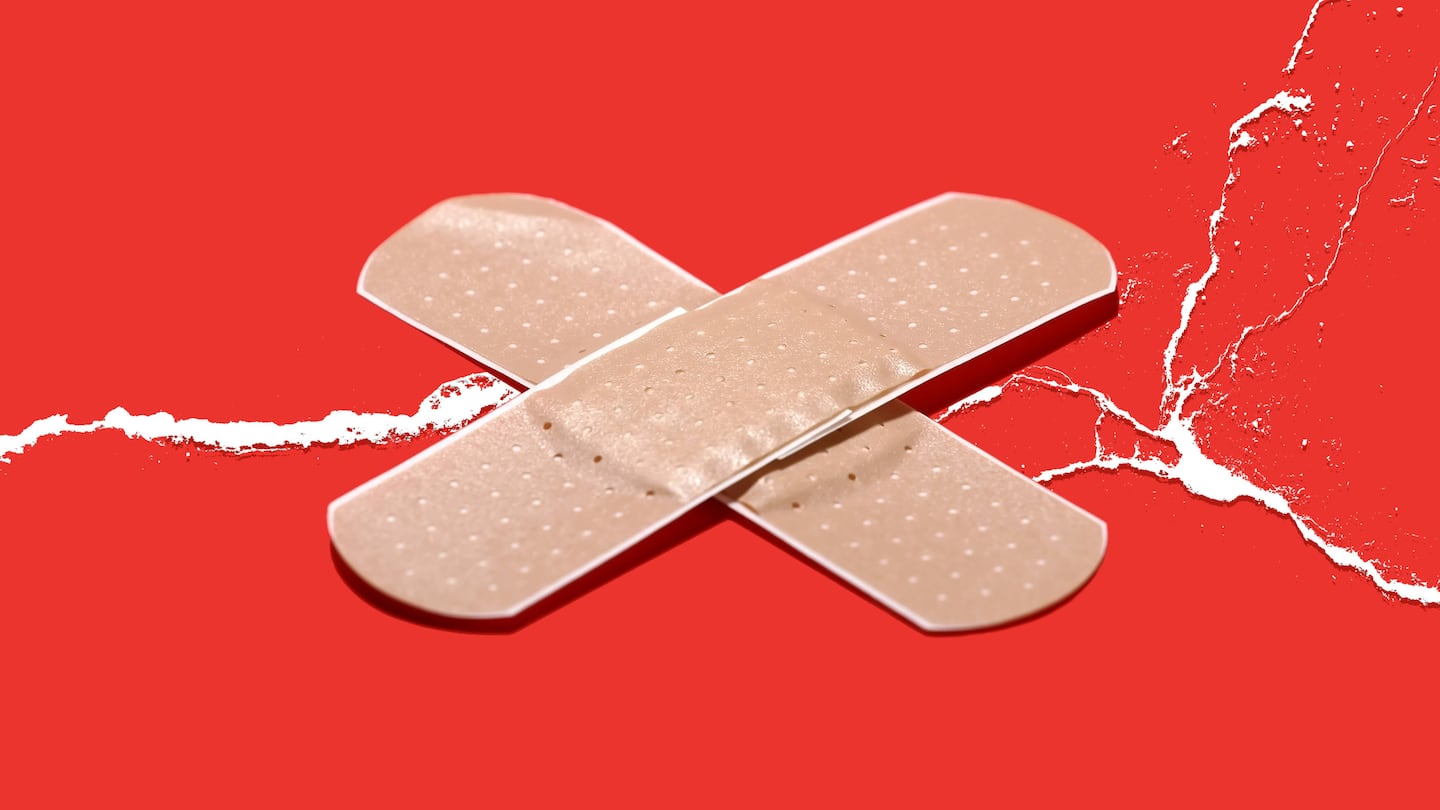 Two adhesive bandages are crossed over a cracked red surface.