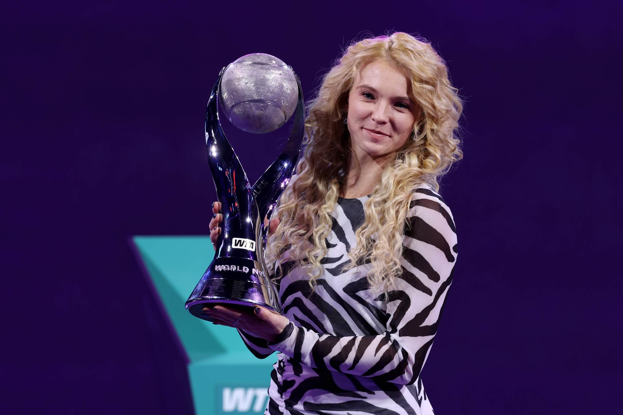Kateřina Siniaková holds a trophy awarded to the women's world No. 1 in doubles, wearing a zebra-print outfit.