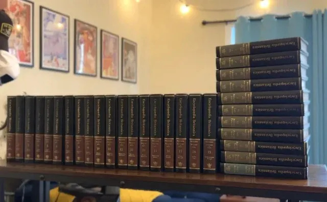 A long row of Encyclopedia Britannica volumes on a table, with a taller stack at the end, suggesting comprehensive information