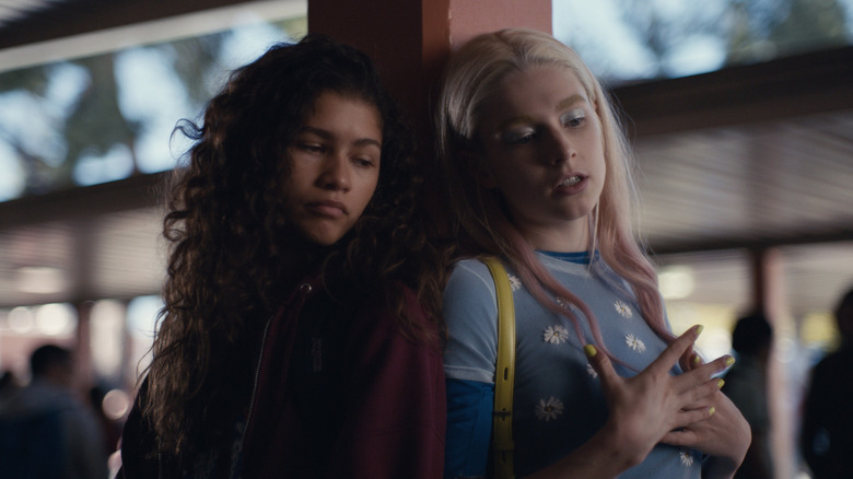 Jules (Hunter Schafer) and Rue (Zendaya) leaning on a column in 