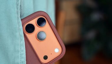 Close-up of a copper-colored smartphone camera module with three lenses and a flash, partially covered by teal fabric.