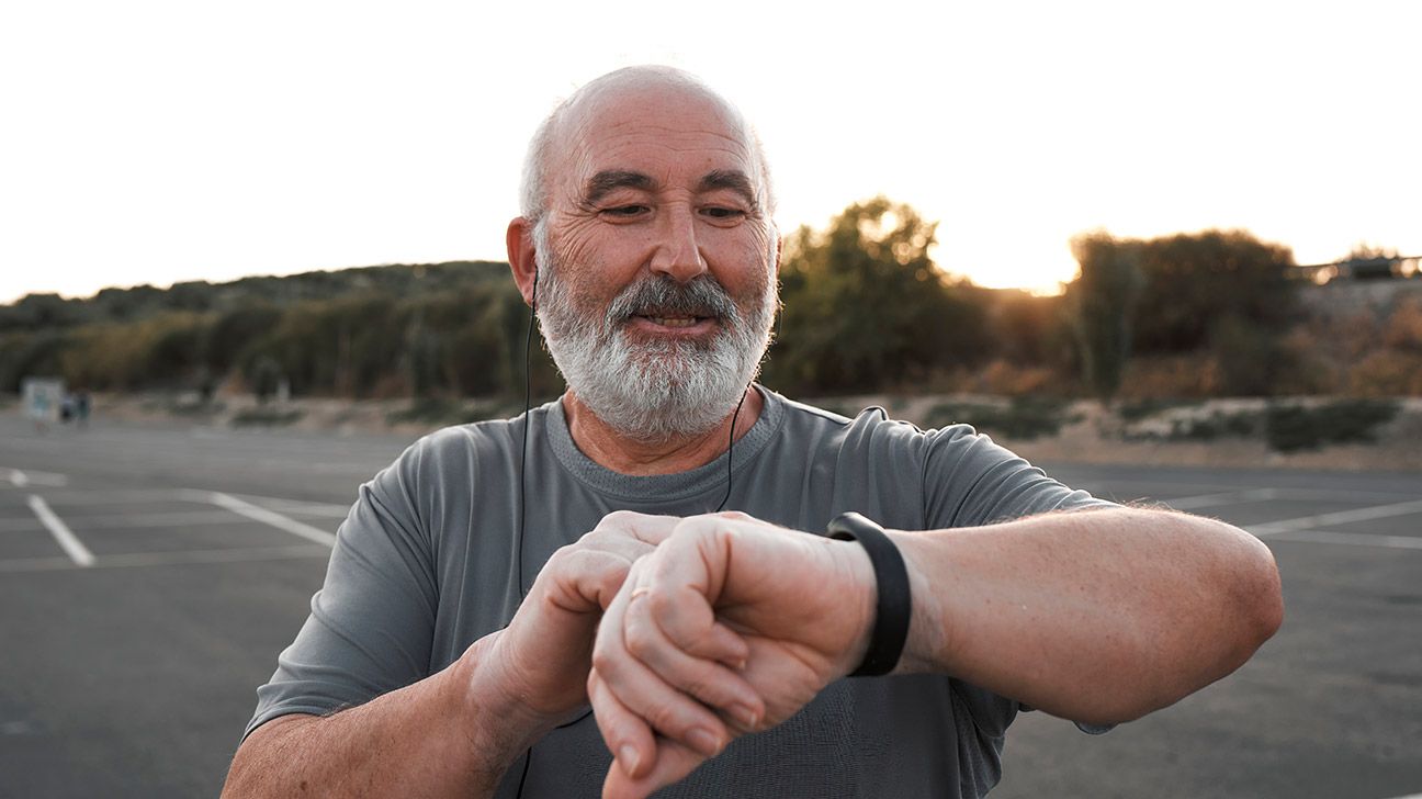 Older male checking fitness tracker outdoors