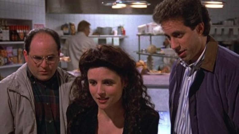 Jason Alexander, Julia Louis-Dreyfus, and Jerry Seinfeld standing in a diner in Seinfeld