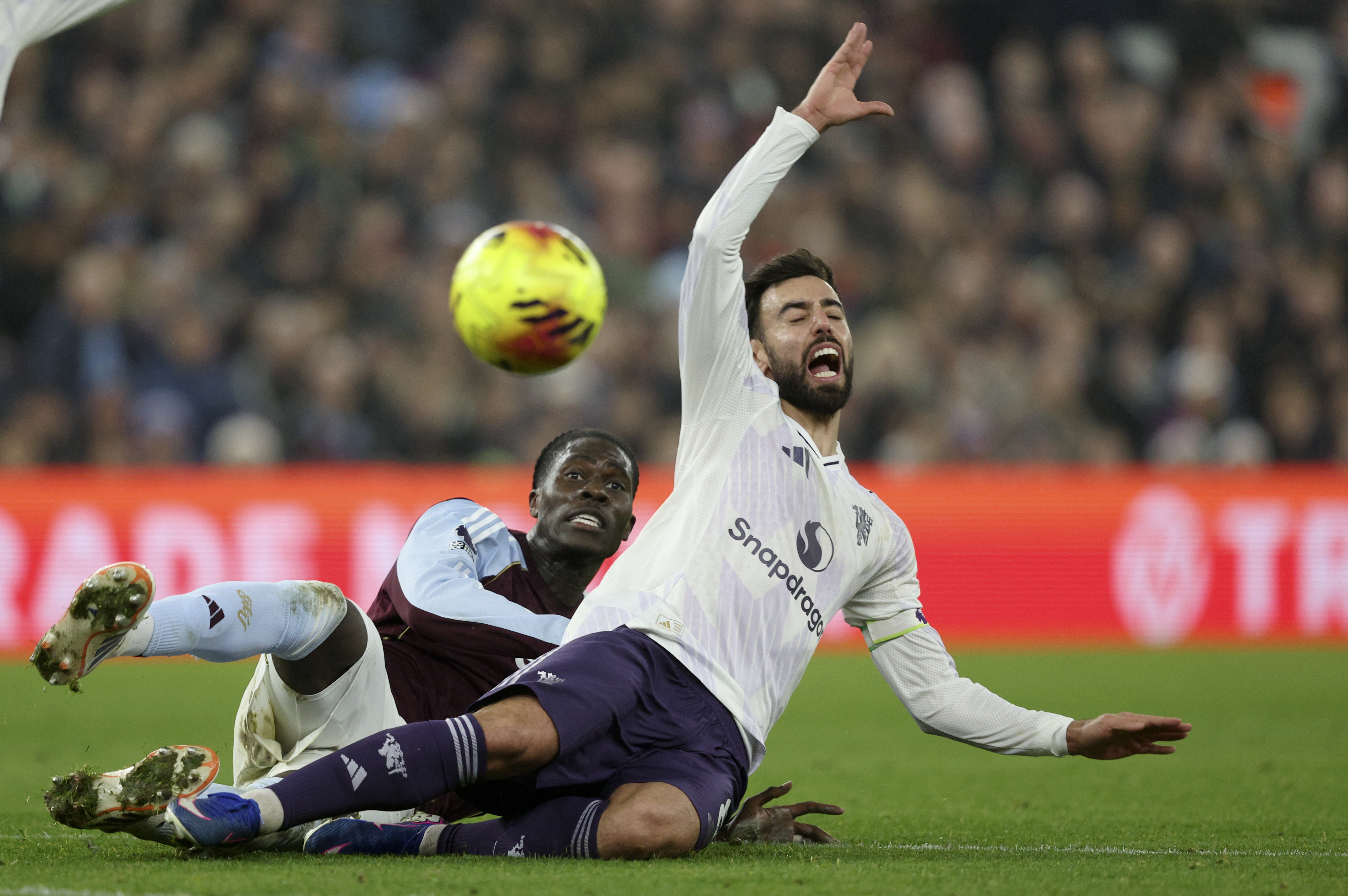 Amadou Onana of Aston Villa challenges Bruno Fernandes of Manchester United during a soccer match.