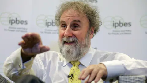 Getty Images Sir Robert Watson in a white shirt and yellow tie during an interview at the IPBES Biodiversity Summit.