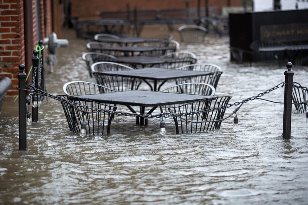 Cafe tables are half submerged as seawater floods Long Wharf in Boston during the storm on Dec. 23, 2022. (Robin Lubbock/WBUR)