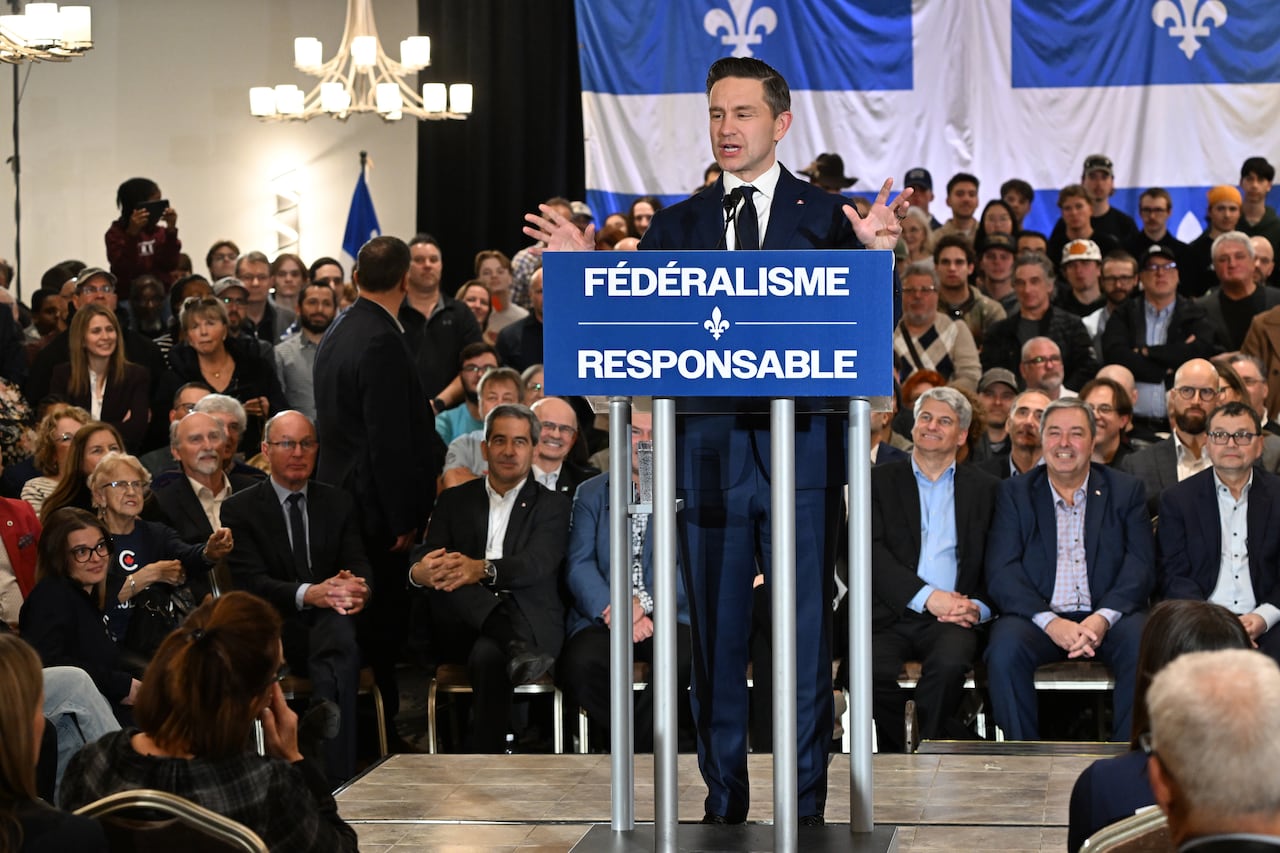 A man stands behind a blue podium in front of a crowd.