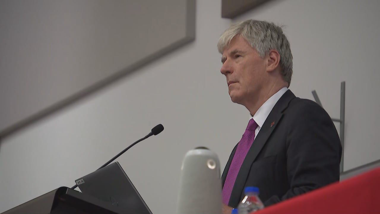 Closeup of Minister Tim Hodgson in a black suit at a red podium