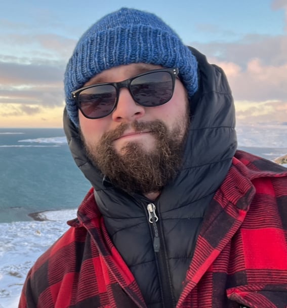 man in red flannel shirt and sunglasses by the ocean