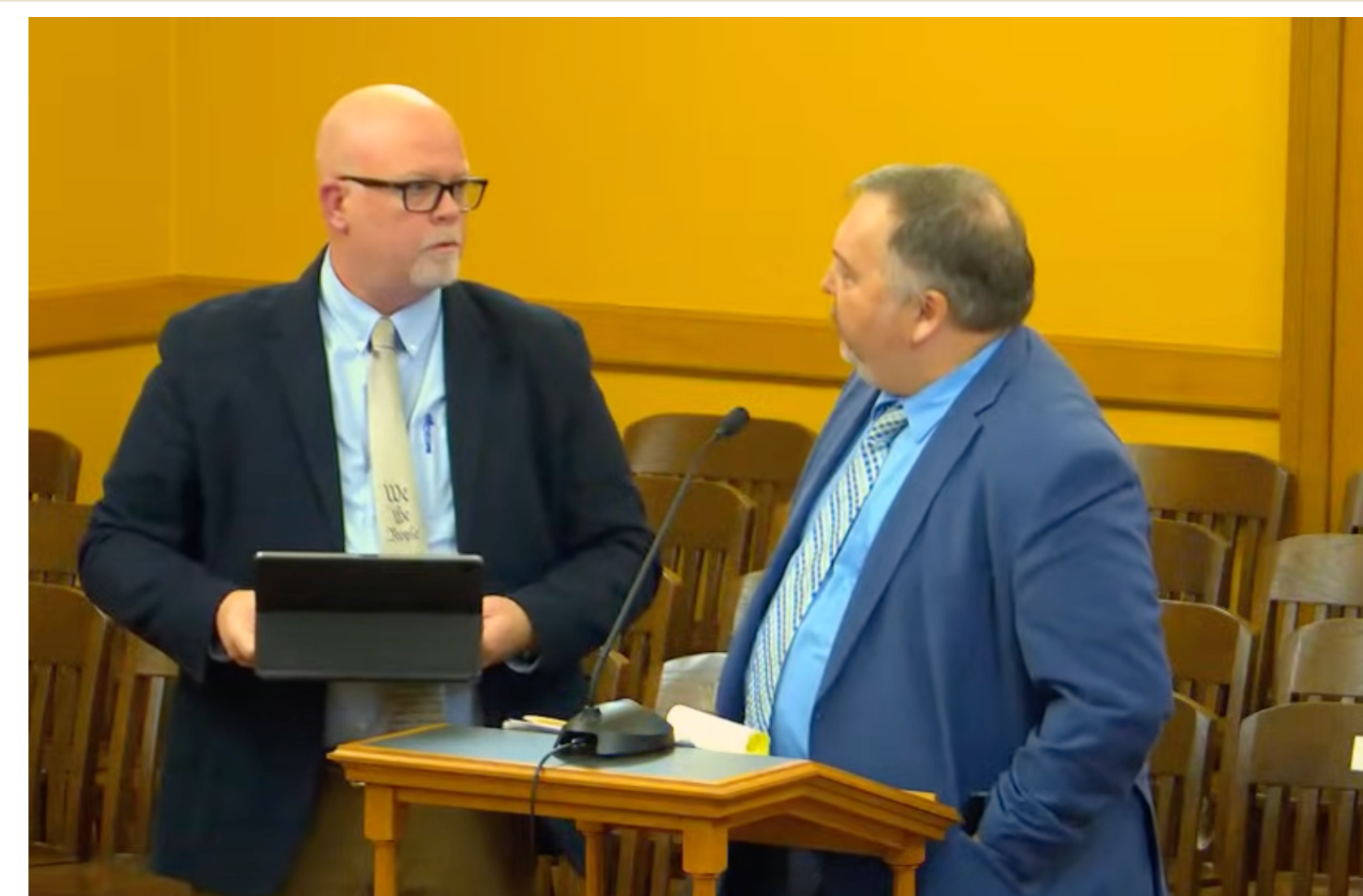  Morton County attorney David Thompson, left, and counsel for the Kansas Department of Revenue Ted Smith, right, tell legislators at a Dec. 2, 2025, meeting in Topeka, Kansas, that the state and county knew of a mistake in local sales tax revenue distribution, but it took ten years to correct it. (Kansas Reflector screen capture of Kansas Legislature YouTube channel)