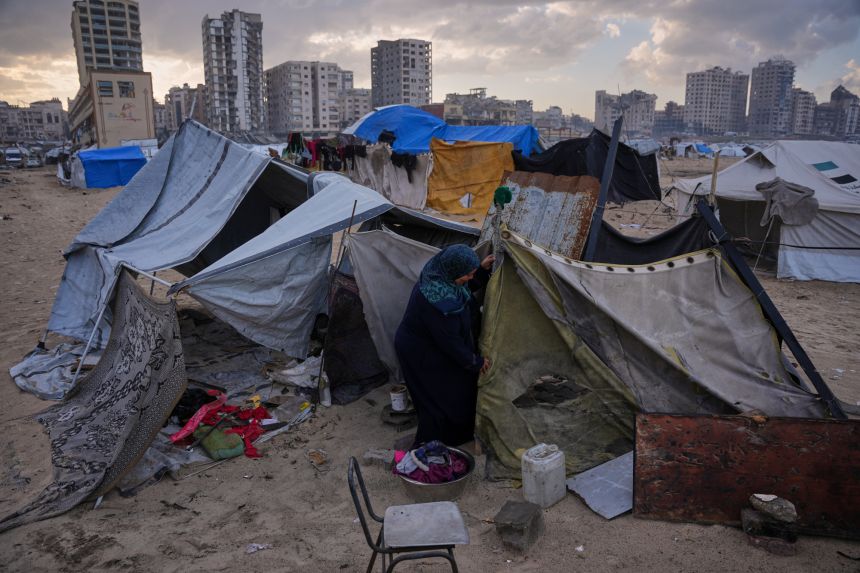 Iman Al-Atoutt repairs her tent after days of rain in a makeshift camp for displaced Palestinians set up on the beach in Gaza City, on December 16.