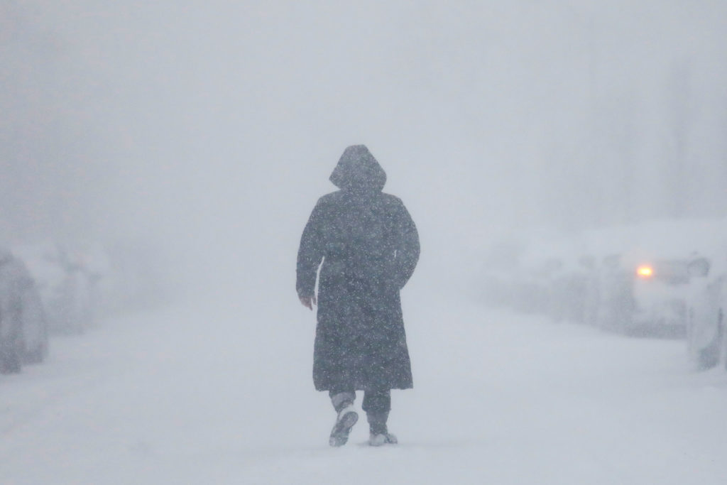 A woman walks down the street during a blizzard in Long Beach