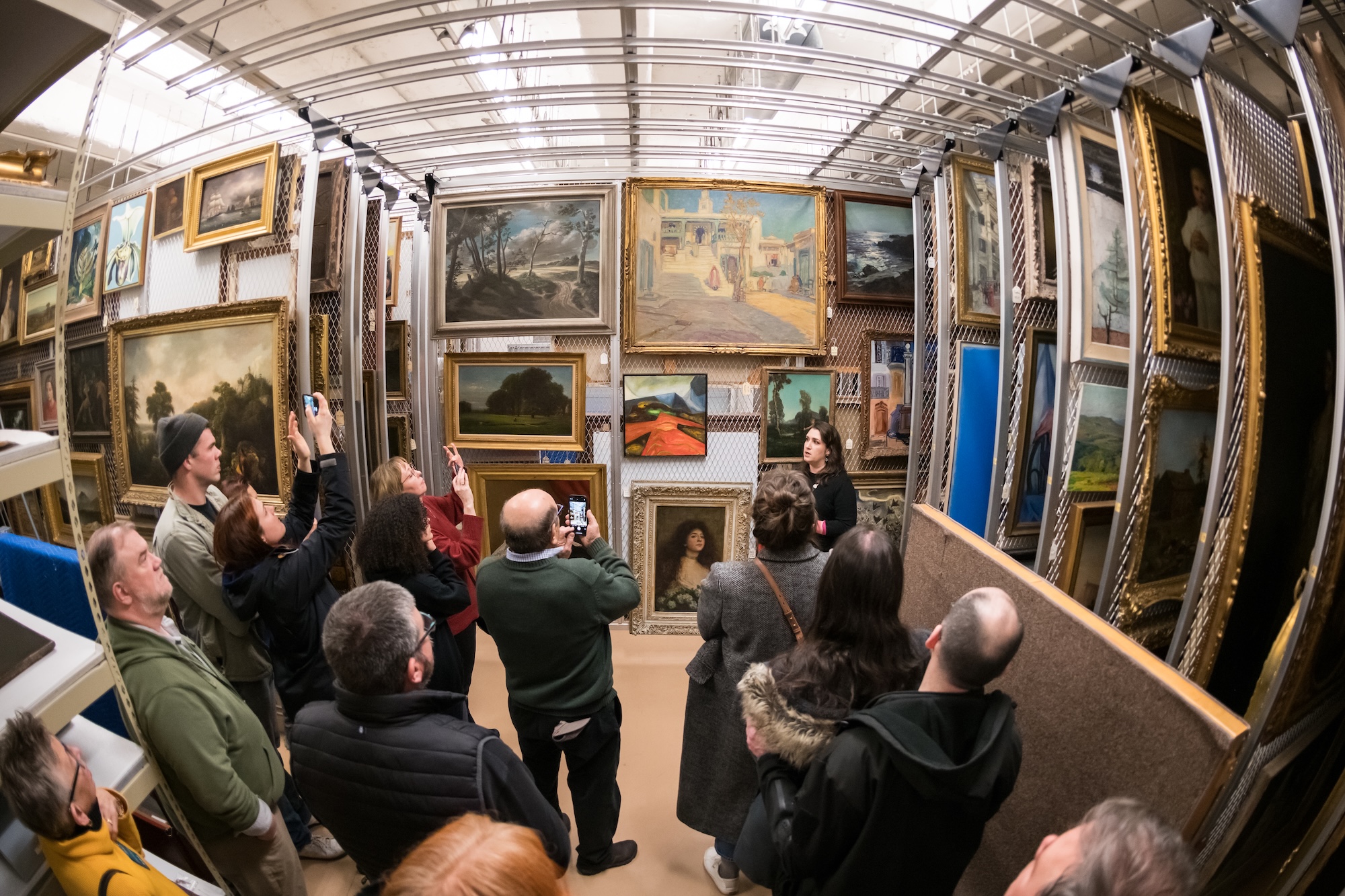 Lauren Tagliaferro, curatorial assistant at the Memorial Art Gallery, speaks to visitors in the painting storage room during a tour.