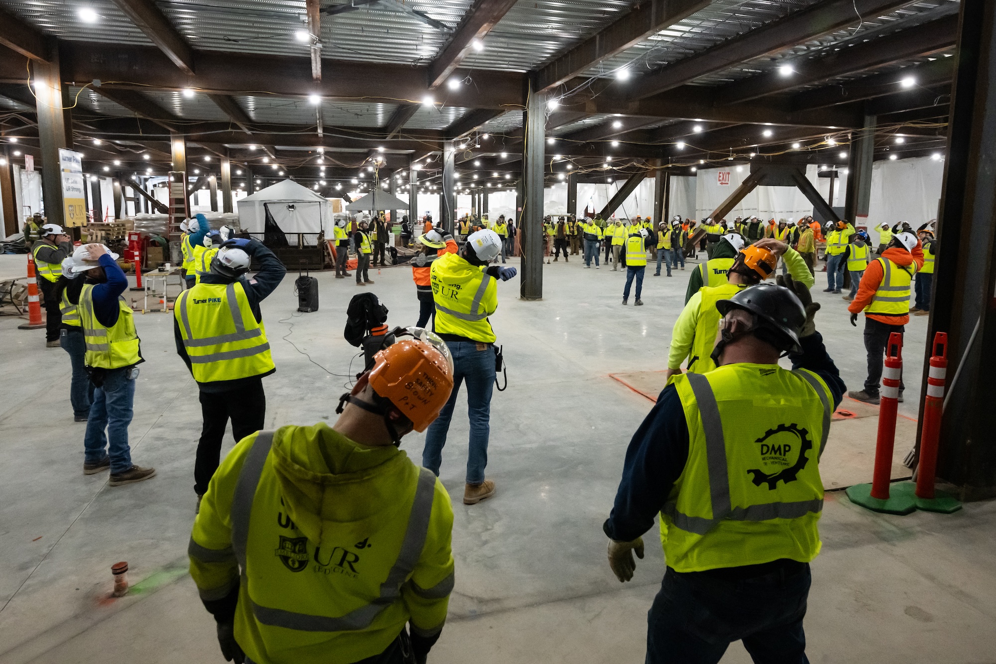 Construction workers gather for a morning stretch .