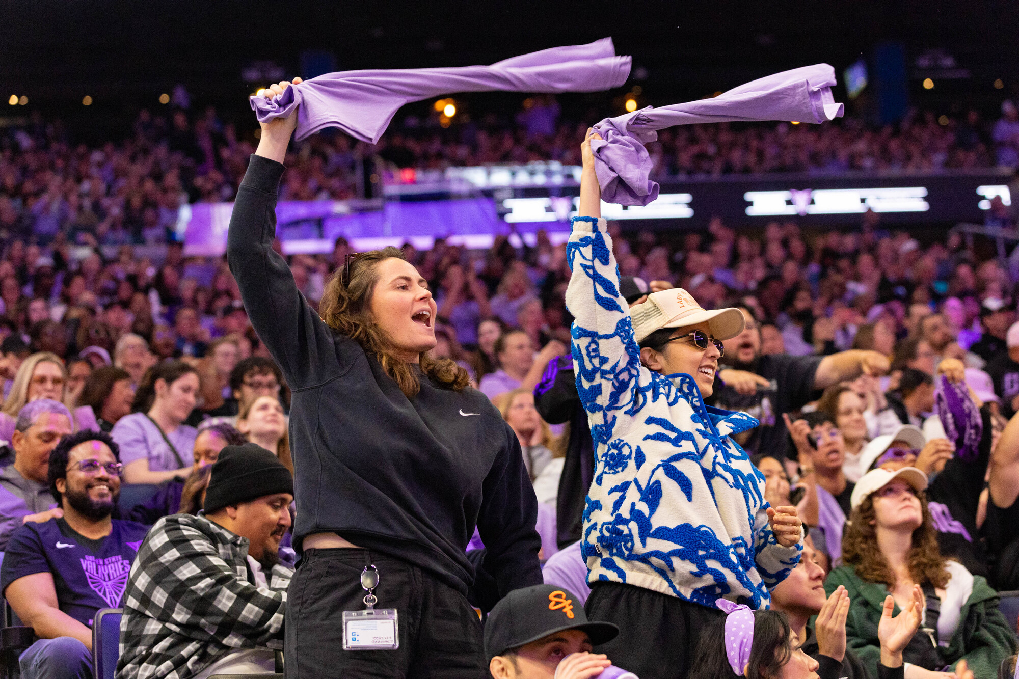 two fans whip lavender shirts over heads in crowd
