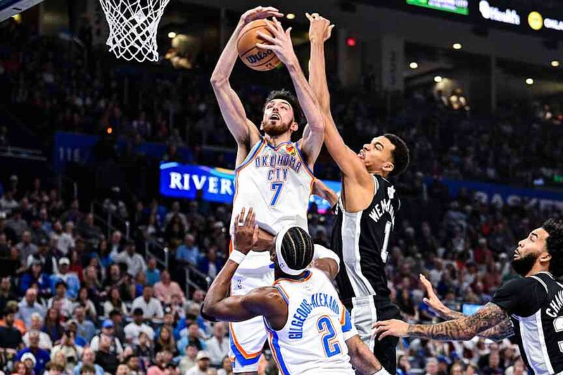 Oklahoma City Thunder Chet Holmgren (7) goes for the rebound against San Antonio Spurs forward/center Victor Wembanyama (1) during the first half of an NBA basketball game, Thursday, Dec. 25, 2025, in Oklahoma City. (AP Photo/Gerald Leong)