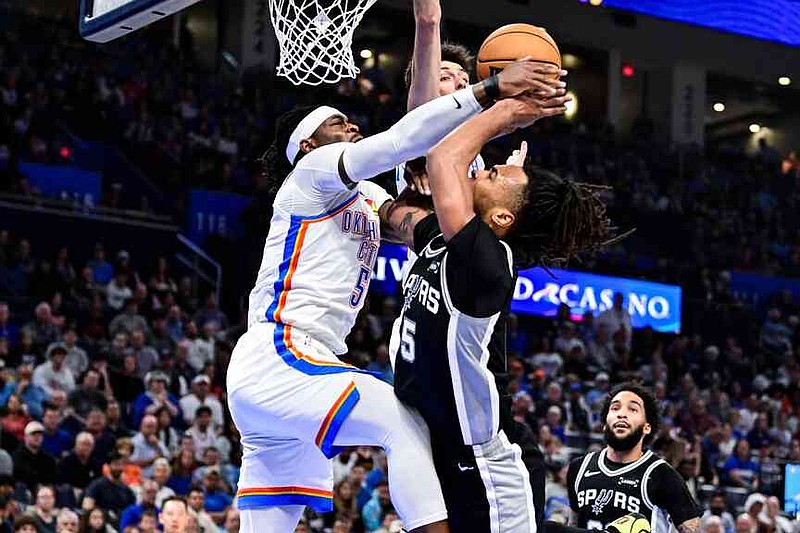 Oklahoma City Thunder guard Luguentz Dort (5) block against San Antonio Spurs guard Stephon Castle (5) during the first half of an NBA basketball game, Thursday, Dec. 25, 2025, in Oklahoma City. (AP Photo/Gerald Leong)