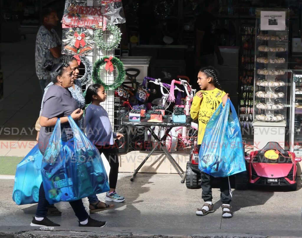 SHOPPING IN SANDO: It was a full and productive day of shopping for these people who walked along High Street in San Fernando clutching bags of items they just purchased. - Photo by Angelo Marcelle