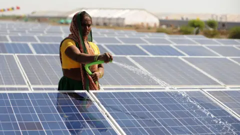 AFP via Getty Images An Indian worker sprays water onto panels of India's first 1MW canal-top solar power plant at Chandrasan village of Mehsana district, some 45 kms from Ahmedabad on World Earth Day, April 22, 2012.