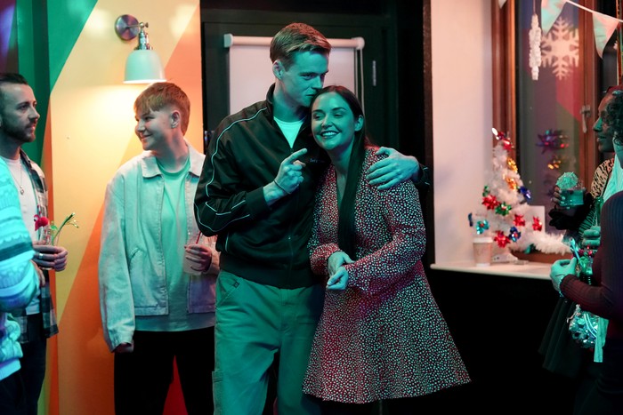 Oscar kisses Lauren on the head surrounded by partygoers in The Prince Albert in a scene from EastEnders