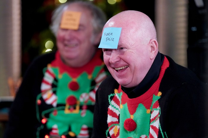 A scene from EastEnders as Nigel Bates and Phil Mitchell sit in Christmas jumpers with post-it notes on their heads. Phil's reads 'Katie Price'.