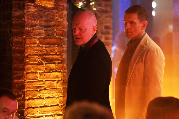 Max stands beside Jack in a golden-lit Harry's Barn in EastEnders.