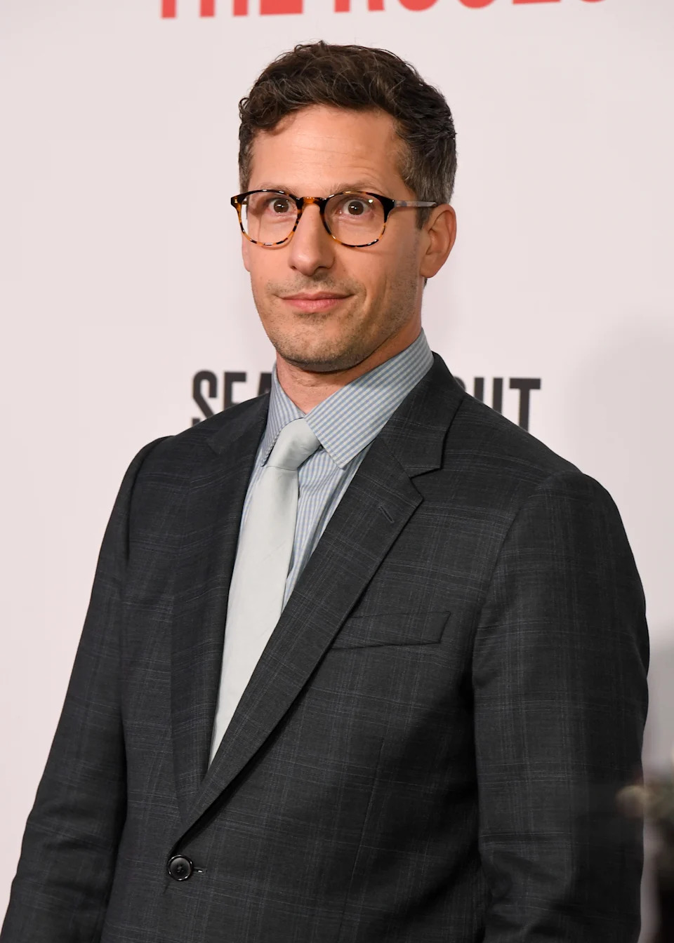 A person in a plaid suit and tie poses at a formal event