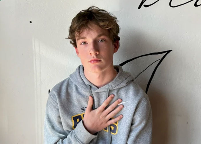 Teenager in a gray hoodie with hand on chest, illustrating concerns around ChatGPT and expert criticism after a tragic incident.