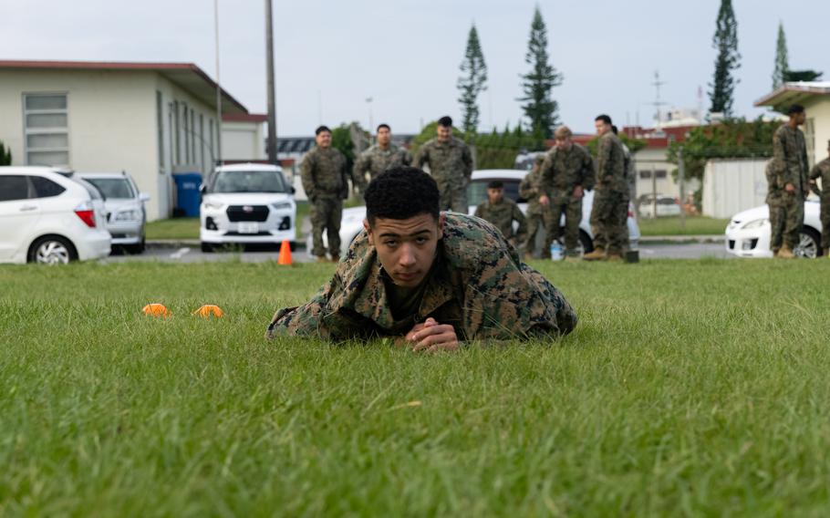 A Marine crawls on the grass while prone.