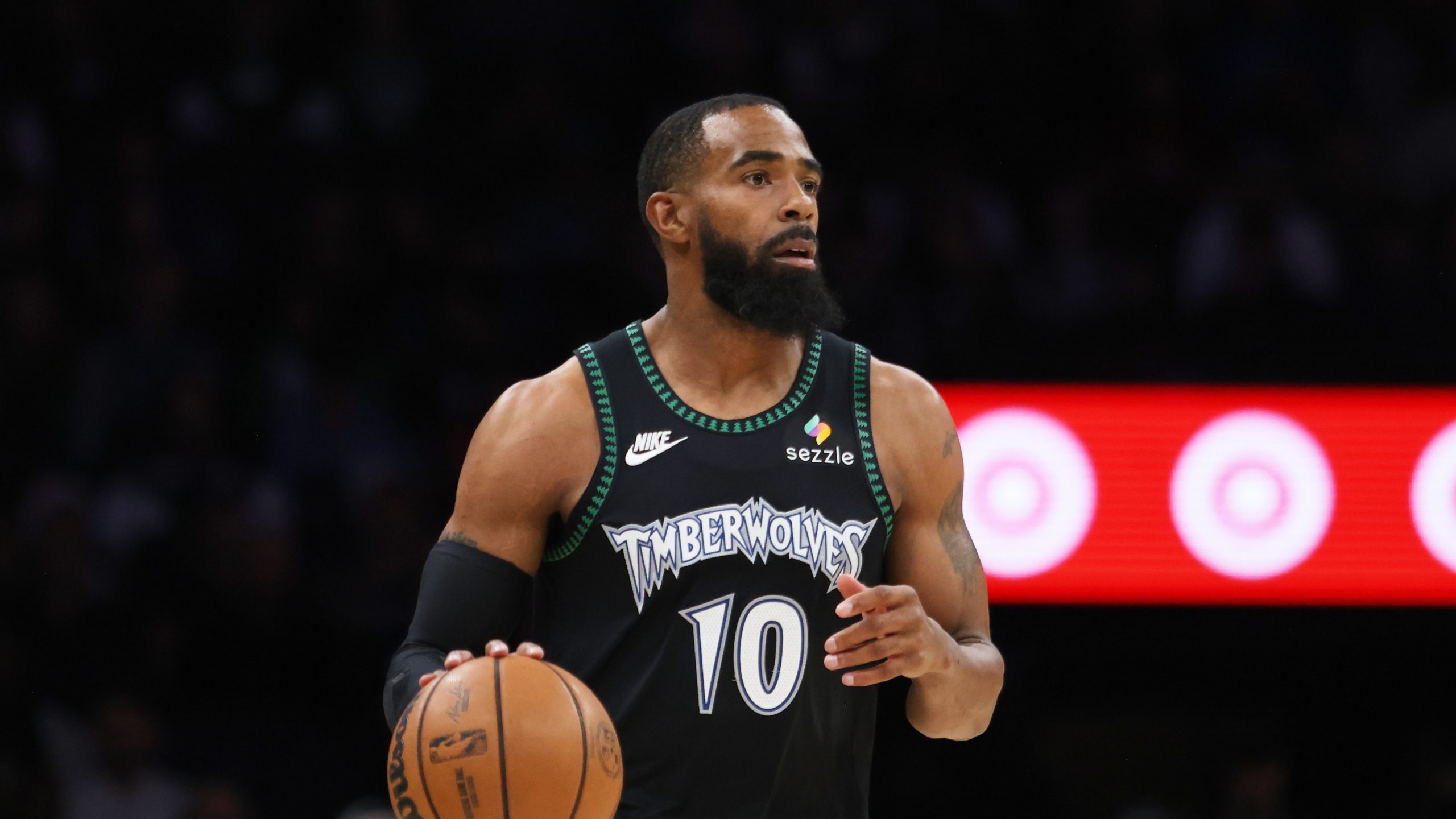 A man dribbles a ball up a basketball court