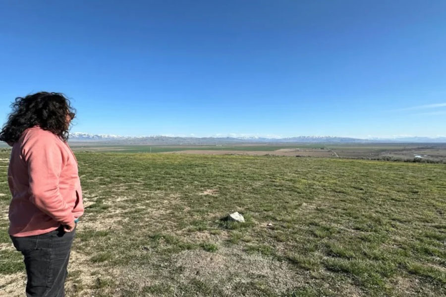 Goli stands atop Ferry Butte, one of the highest points on the Fort Hall Reservation in Idaho, and scans the sparsely populated landscape. | Sarah Jane Tribble, KFF Health News