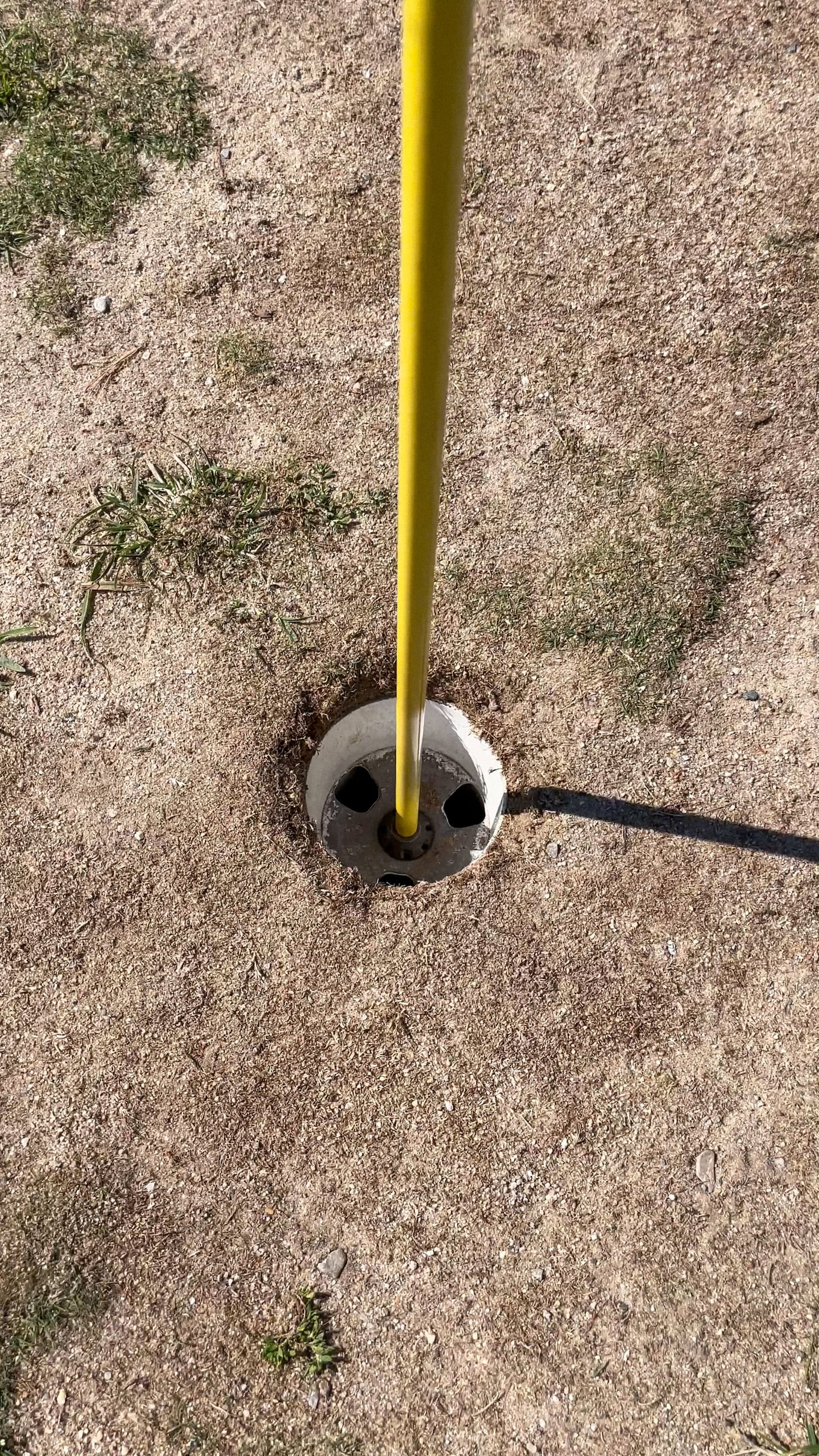 A close-up image of a hole surrounded by hard, dry dirt.